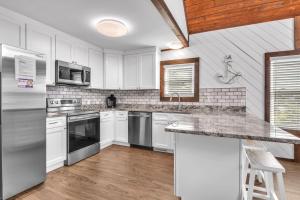 a kitchen with white cabinets and stainless steel appliances at Salty Dawg by Oak Island Accommodations in Oak Island