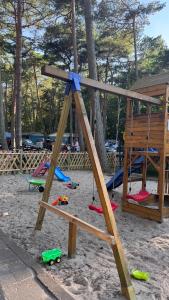 a playground with swings and toys in the sand at Feriensiedlung Schwalbennest - Bungalows in Dranske