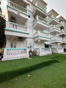 a large building with a green lawn in front of it at Sunshine Park By RoomzAway in Candolim