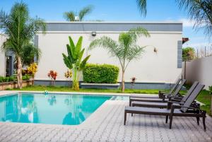 a swimming pool with two chairs next to a building at Muka Staytel in Ndola