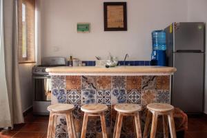 a kitchen with a counter with stools and a refrigerator at Kay Apartments Isla Mujeres in Isla Mujeres