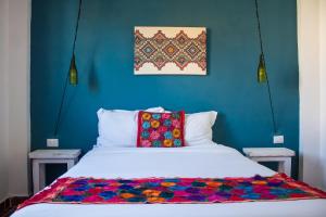 a bedroom with a white bed with a colorful blanket on it at Kay Apartments Isla Mujeres in Isla Mujeres