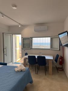 a bedroom with a table and chairs and a room with windows at Terracina Seaside Apartments in Lido Di Fondi +246 photos