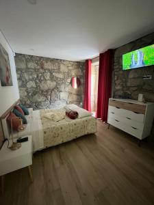 a bedroom with a bed and a stone wall at Casa De Cantoneiros in Campos