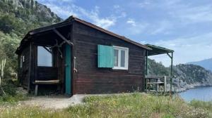 a small house on a hill next to a body of water at Fitalmios in Methana
