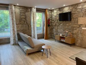 a living room with a couch and a tv on a stone wall at Casa De Cantoneiros in Campos