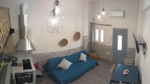 a living room with a blue couch and pendant lights at AJ studios by the Sea in Kithnos