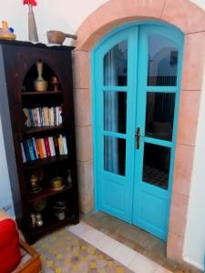 a blue door in a room with a book shelf at Dar darkom in Essaouira