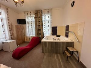 a large bathroom with a tub and a red ottoman at LuxInn in Bucharest