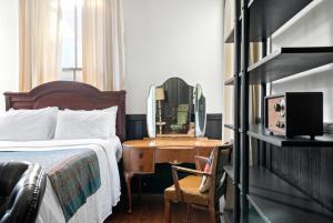 a bedroom with a bed and a desk with a mirror at Saint Helens House-Hotel Historic District Near Cruise Port in Galveston
