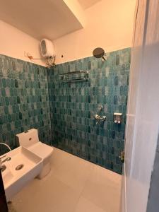 a green tiled bathroom with a toilet and a sink at Sunshine Park By RoomzAway in Candolim