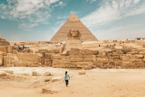 a woman walking in front of the pyramids at Kemet Pyramids Apartments in Cairo