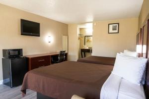 a hotel room with two beds and a television at Rodeway Inn Monroe in Monroe