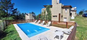 a swimming pool with chairs and a house at Terrazas de Nahuascat in Santa Rosa de Calamuchita