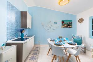 a kitchen with blue walls and a white table and chairs at Blue View - A Due Passi dal Mare & Natura in Quartu SantʼElena