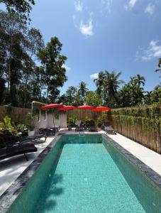 a swimming pool with chairs and umbrellas at Aranya Bliss Villa 104 in Wok Tum
