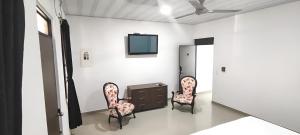 Ein Zimmer mit zwei Stühlen und einem Fernseher an der Wand in der Unterkunft Hotel San Rin in Nilo