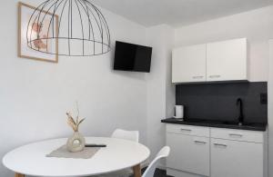a white kitchen with a white table and aendant light at Royans Ferienwohnung in Günzburg
