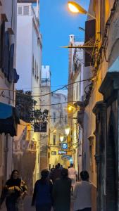 a group of people walking down a street at night at Dar darkom in Essaouira