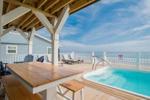 a deck with a wooden table and a swimming pool at Saltwater Blessing by Oak Island Accommodations in Oak Island