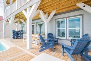 a porch with blue chairs and a table and a swimming pool at Saltwater Blessing by Oak Island Accommodations in Oak Island