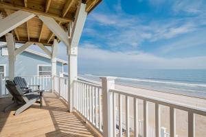 a porch of a house with a bench on the beach at Saltwater Blessing by Oak Island Accommodations in Oak Island