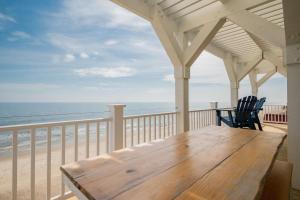a porch with a wooden table and chairs on the beach at Saltwater Blessing by Oak Island Accommodations in Oak Island +98 photos