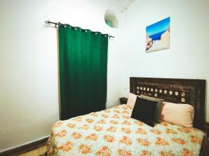 a bedroom with a bed with a green curtain at Dar darkom in Essaouira