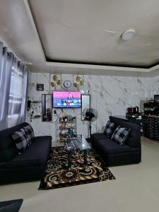 a living room with two black couches and a tv at PrincessStar in Pagadian