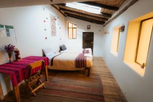 a bedroom with a bed and a table in it at Sonidos del Ande Wasi in Pisac