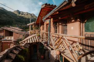 a building with a wooden staircase next to a mountain at Sonidos del Ande Wasi in Pisac