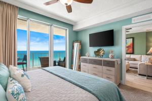 a bedroom with a bed with a television and a balcony at Luxury Beachfront Condo Free Beach Chairs Huge Balcony Come Relax! in Panama City Beach