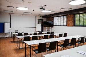 ein Klassenzimmer mit Tischen, Stühlen und einer Tafel in der Unterkunft Aktivhotel Wildschütz in Gmunden