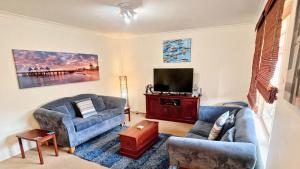 a living room with two couches and a flat screen tv at The Orchid Courthouse - Busselton in Geographe