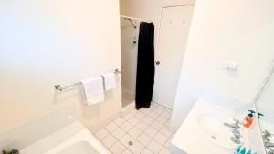 a white bathroom with a shower and a sink at The Orchid Courthouse - Busselton in Geographe +24 photos