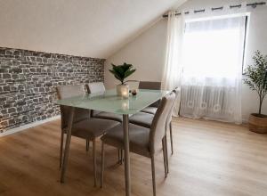 a dining room table with chairs and a brick wall at Helle Ferienwohnung im Schwarzwald - 2 Schlafzimmer - WLAN - Holzapfel Apartments in Villingen-Schwenningen