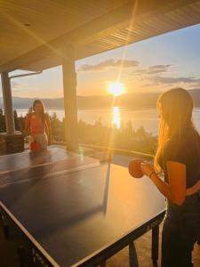 two girls sitting on a ping pong table watching the sunset at Lakeview Bed and Breakfast in Kelowna