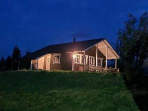 a house with a light on the side of a field at Cozy cabin close to nature in Sorreisa
