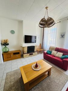 a living room with a red couch and a table at La Maison du Chenal in Gravelines