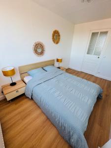 a bedroom with a large bed with a blue comforter at La Maison du Chenal in Gravelines