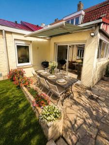 a patio with a table and chairs and flowers at La Maison du Chenal in Gravelines