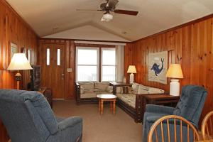 a living room with wooden walls and a couch and chairs at Blue Haven by Oak Island Accommodations in Oak Island