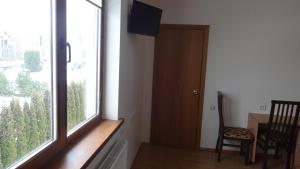 Habitación con ventana, silla y mesa. en Vidų Guest House, en Utena