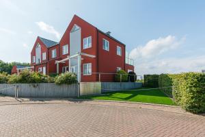 a red house with a fence in front of it at FeWo Sanfte Brise im EG mit Blick in die Natur in Göhren-Lebbin