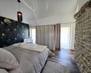 a bedroom with a bed and a brick wall at Gite Les Petits Monts in Commes
