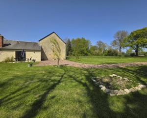a house with a large shadow on the grass at Gite Les Petits Monts in Commes