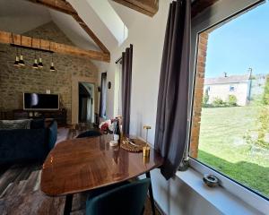 a living room with a wooden table and a large window at Gite Les Petits Monts in Commes