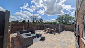 a patio with a bench and a table and a fence at The Wimpey At Mill Cottage in Bedford