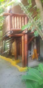 ein Holzgebäude mit Veranda und einem Baum in der Unterkunft Bongosurfcamp in Mompiche