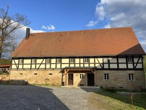 an old stone building with a red roof at Vierseithof "Waitzdorfer Hof" in Hohnstein